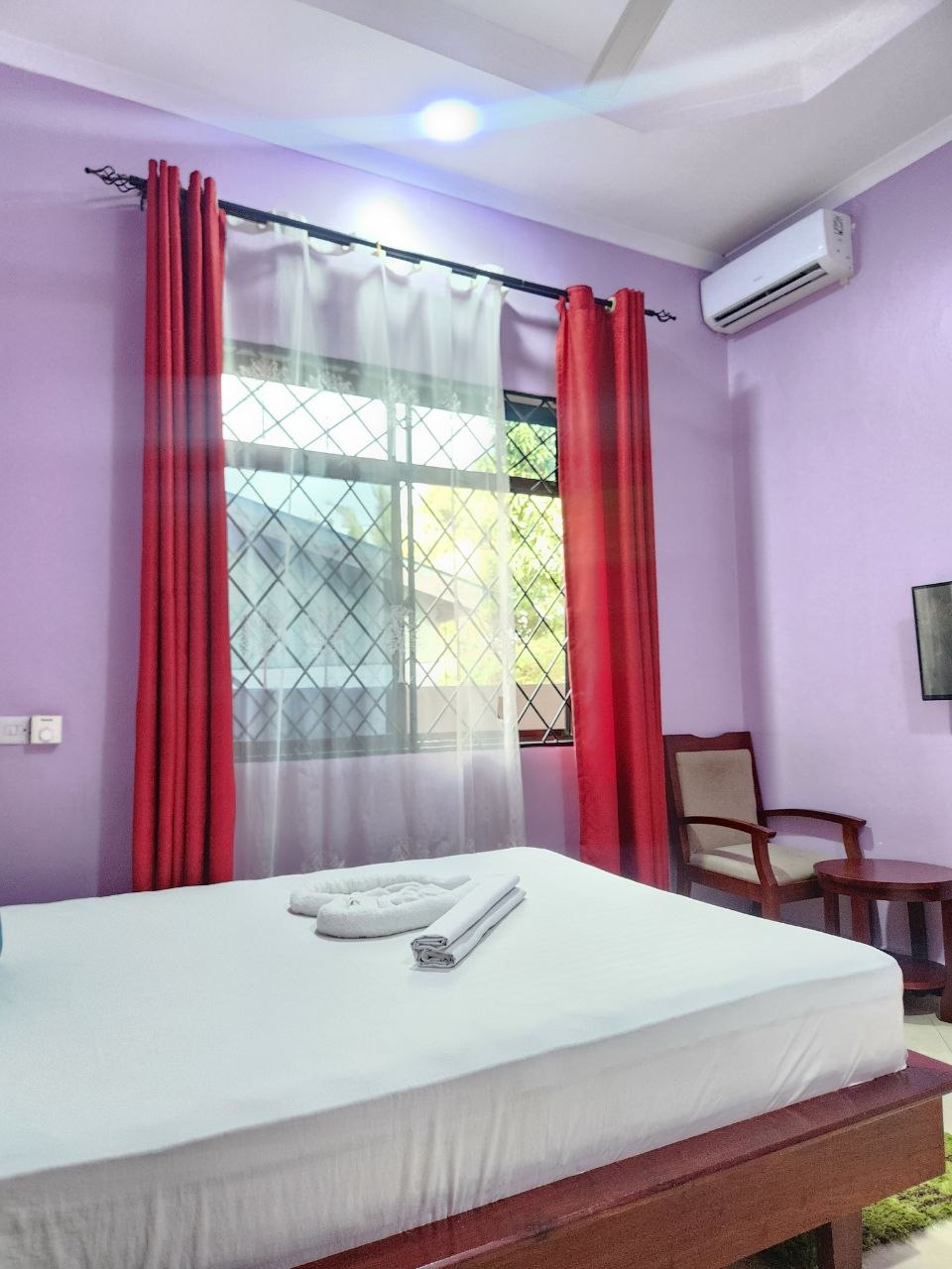 Purple-walled king room with red curtains